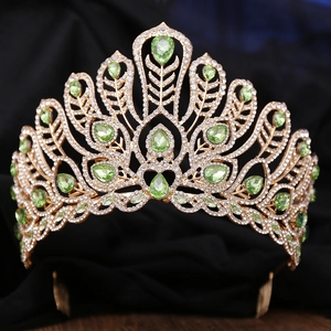 Detailed close-up of golden crown featuring green pear-cut crystals and a metal hair comb