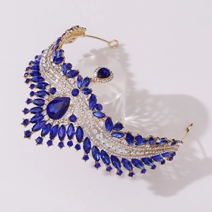 Macro detail of royal gold crown featuring teardrop blue gemstone and crystal accents