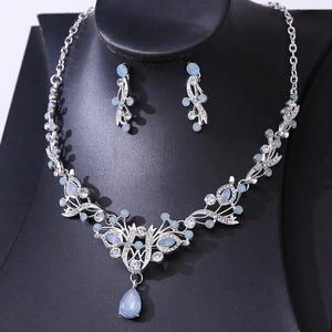 Detail shot of light blue teardrop crystal necklace and earrings set on black display