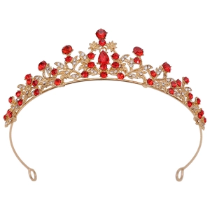 Close-up of golden bridal crown with red rhinestones and floral vine structure detail