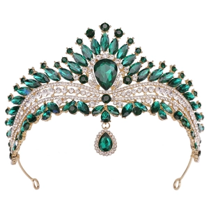 Close-up of golden crown with emerald drop pendant and sparkling crystal details