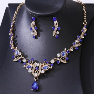 Detail view of gold bridal jewelry set with navy blue crystals and floral leaf patterns
