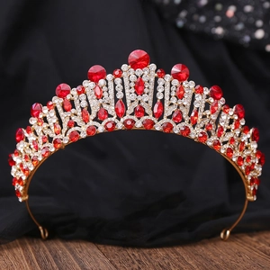 Close-up of golden bridal tiara with red and white crystals on black fabric background
