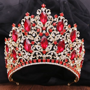 Close-up of golden bridal crown with luxury red crystals and leaf-shaped rhinestones