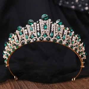 Close-up of golden crown with emerald green and clear crystals on dark lace