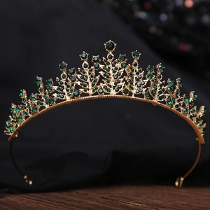 Detail of a vintage golden bridal tiara featuring emerald green crystals on wood