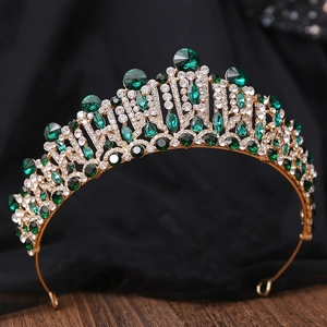 Detail shot of vintage golden crown with emerald green gems and white crystal rhinestones