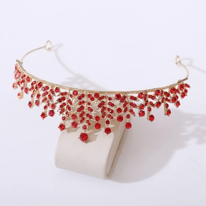 Close-up of golden bridal crown with red rhinestones and intricate leaf design details