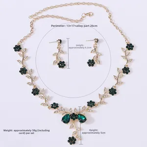 Detail view of gold-tone floral necklace and earrings set with green rhinestones