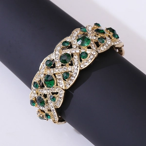 Close-up of luxury gold-plated cuff bracelet with green emerald crystals and clear diamonds