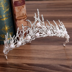 Silver bridal tiara crown with handmade pearls and coral branch design on wood background