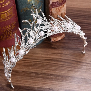 Close-up of handmade silver branch bridal crown with white pearls on vintage book