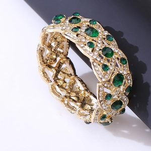 Detail of vintage gold-plated stretch bracelet with green gemstones and white crystals