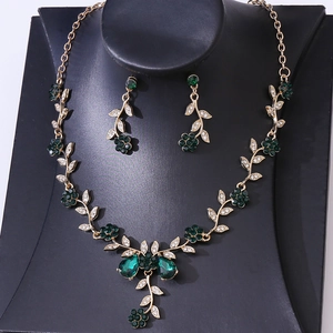 Macro shot of dark green flower rhinestone necklace and earrings set on black jewelry stand