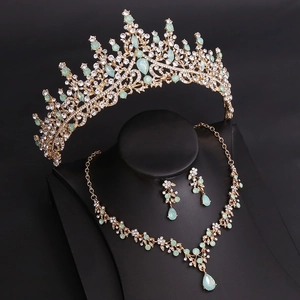 Detail of bridal jewelry set with green gemstones, crown necklace and earrings