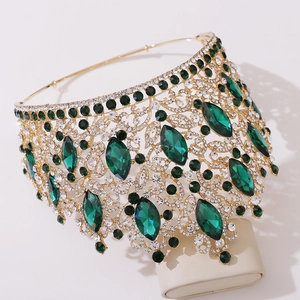 Macro detail of luxury baroque crown featuring emerald green gems and gold leaf-style plating