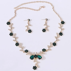 Close-up of vintage gold floral necklace set with emerald green crystals and diamonds