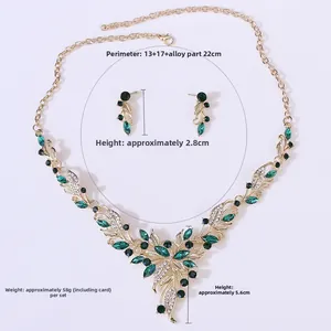 Detail view of gold leaf necklace and emerald earrings set with size measurements