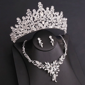 Macro shot of bridal jewelry set with crystal crown and leaf necklace on black display
