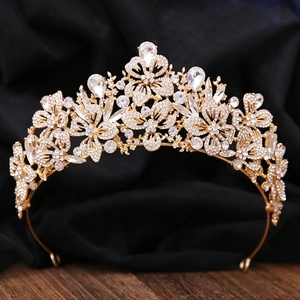 Detailed close-up of golden leaf crown featuring intricate rhinestones on a black background
