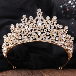 Detailed view of golden bridal tiara with intricate hollow patterns and teardrop crystal