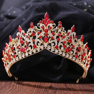Primer plano de corona barroca dorada con cristales rojos de pera y detalles de metal calado