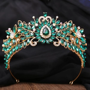 Détail de la couronne dorée vintage avec cristaux émeraude et strass sur satin noir