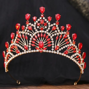 Detail view of gold baroque crown featuring red teardrop crystals and ornate filigree