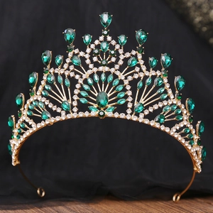 Detail of a vintage golden baroque crown with emerald crystals and sparkling rhinestones