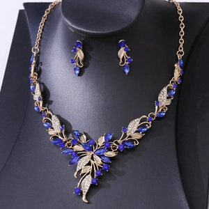 Detailed close-up of golden floral leaf necklace set with deep blue crystals and white gems