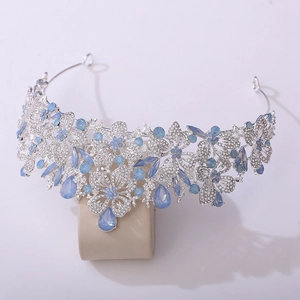 Close-up of silver bridal crown with leaf patterns and blue teardrop rhinestones