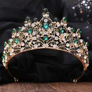 Detailed macro of a vintage gold tiara featuring teardrop emeralds and white crystals