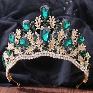 Detail of baroque gold crown featuring emerald green crystals and leaf textures