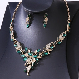 Macro detail of bridal jewelry set featuring green crystals and gold leaf patterns