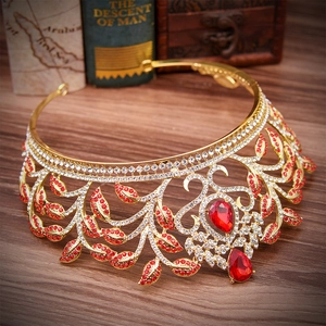 Macro detail of luxury gold bridal crown with leaf patterns and red rhinestone teardrops