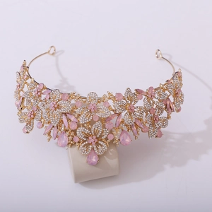 Close-up of golden bridal tiara featuring pink crystals and intricate leaf rhinestones