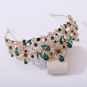 Macro detail of Baroque gold tiara with green rhinestones and floral leaf patterns