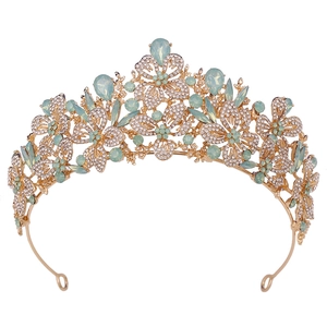 Detailed view of the golden tiara with green pear-cut crystals and floral rhinestones