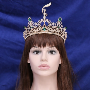 Detail of gold tiara featuring green emeralds and intricate leaf patterns for pageants