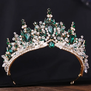 Detailaufnahme einer goldenen Brautkrone mit grünen Kristallen auf dunklem Holzuntergrund