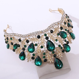 Detailed macro of a gold bridal crown featuring teardrop emerald crystals and leaf patterns