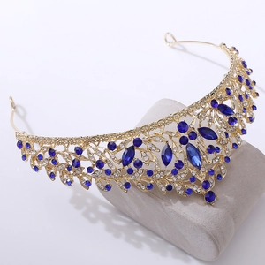 Macro view of golden crown with deep blue rhinestones and intricate hollow scrollwork