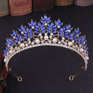 Detailed view of the gold crown with blue crystal leaves and white pearls decorations