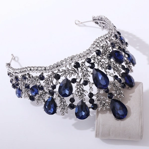 Macro detail of Baroque silver crown featuring deep blue teardrop crystal and leaf design