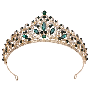 Close-up of golden crown with marquise emerald gems and white crystal details