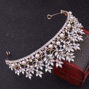 Close-up of golden baroque bridal crown with white crystals and pearls on vintage box