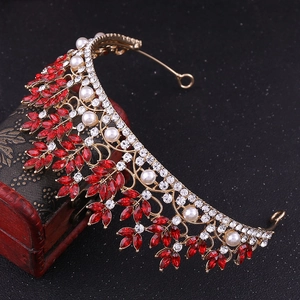 Detailed macro view of gold bridal tiara with red crystal leaves and white pearls