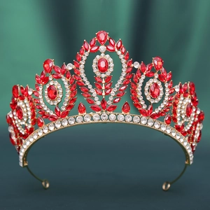 Detailed close-up of Baroque gold crown with red gemstones on dark green silk