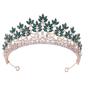 Detailed macro view of gold baroque crown featuring emerald green leaves and pearls