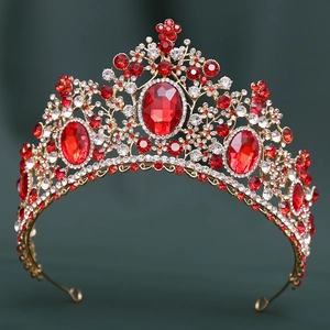 Detailed view of Baroque crown with red rubies and gold base on green fabric
